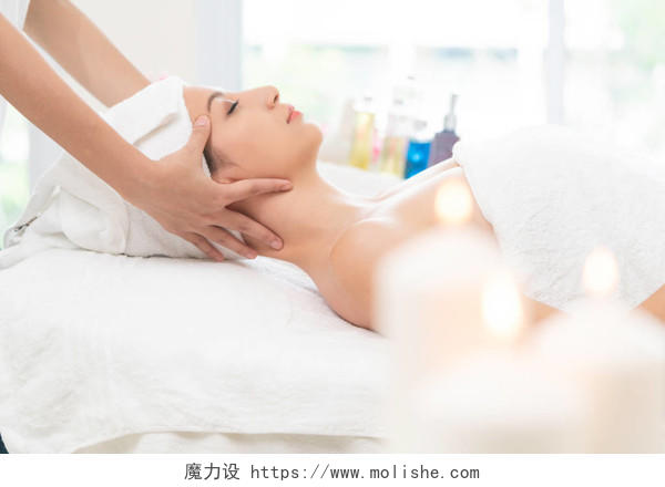 妇女躺在床上接受按摩治疗师的面部和头部按摩治疗放松面部清洁脸部面部按摩中医养生头部按摩